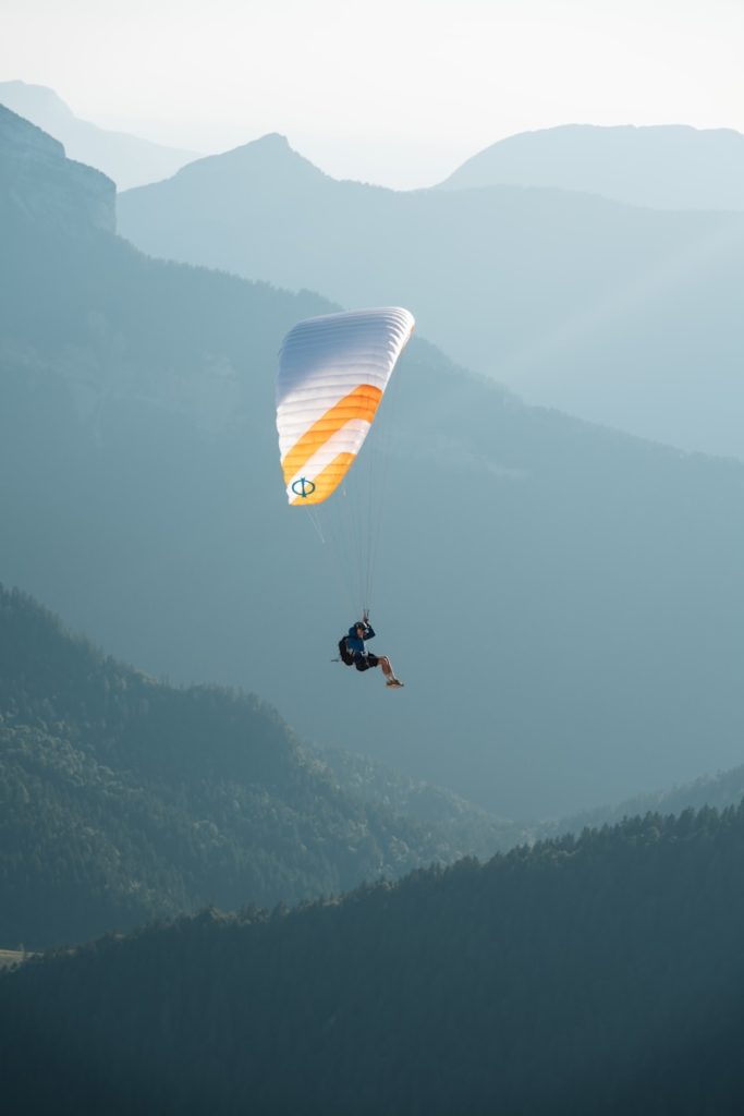Paraglider soaring over misty mountains